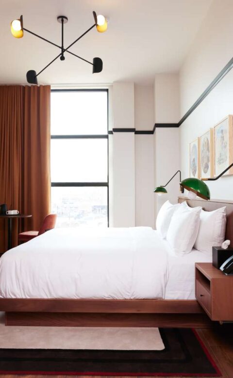 a bed room with a neatly made bed and a chair