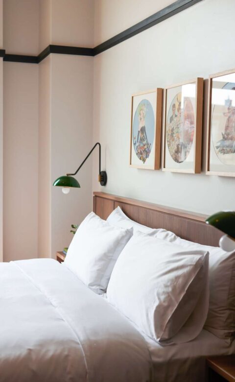 a bed with white sheets and pillows in a bedroom