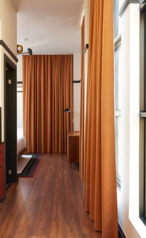 a long narrow hallway with a red cabinet next to a window