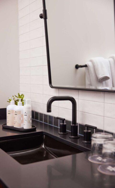 a bathroom with a sink, mirror and soap dispenser