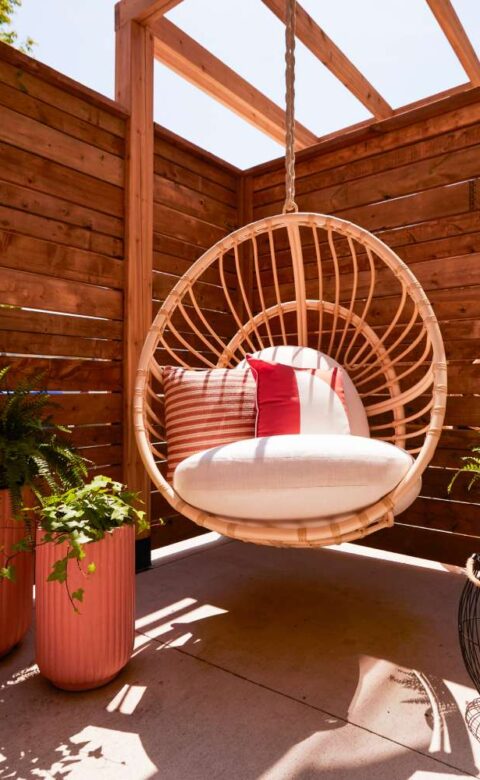 a hanging chair on a patio with potted plants