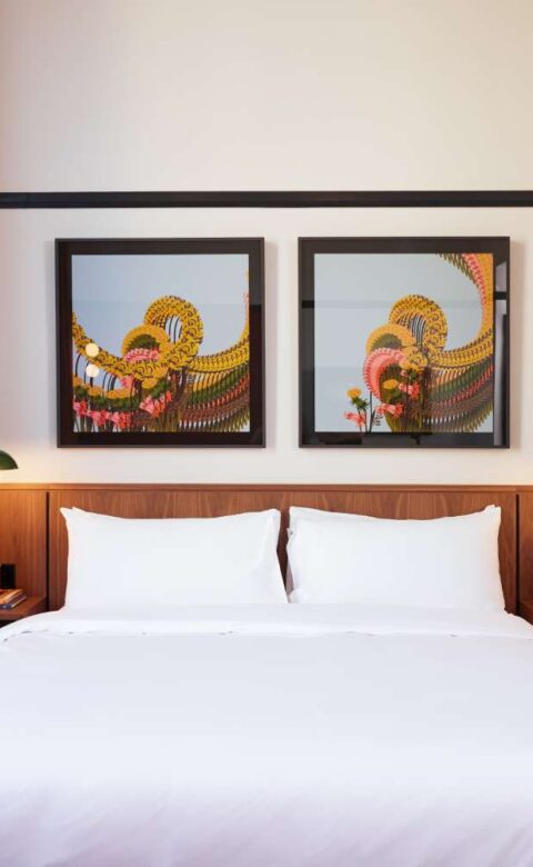 a bed with a white comforter and two pictures on the wall