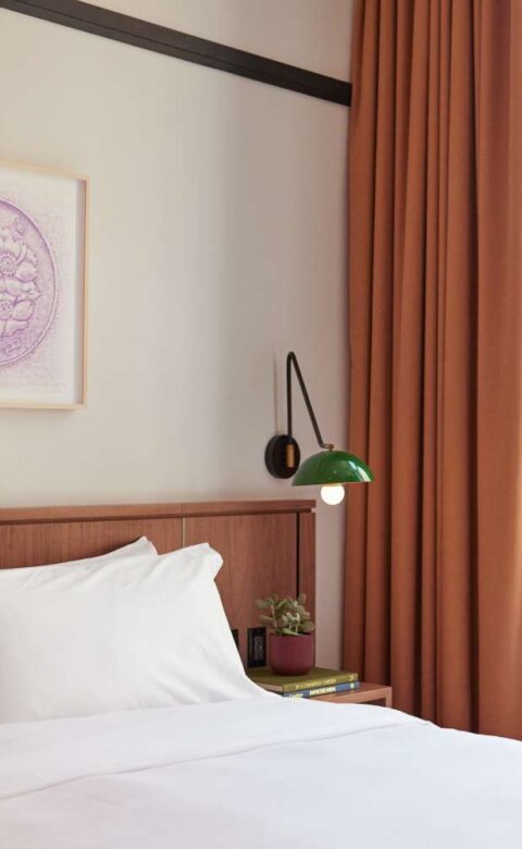 a bed with white sheets and pillows in front of a window