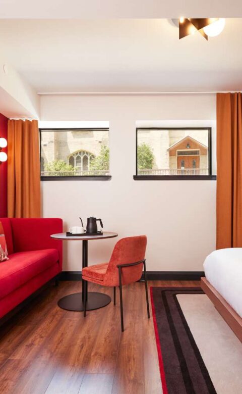 a hotel room with a red couch and a white bed