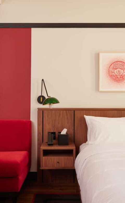 a bedroom with a red accent wall and a white bed