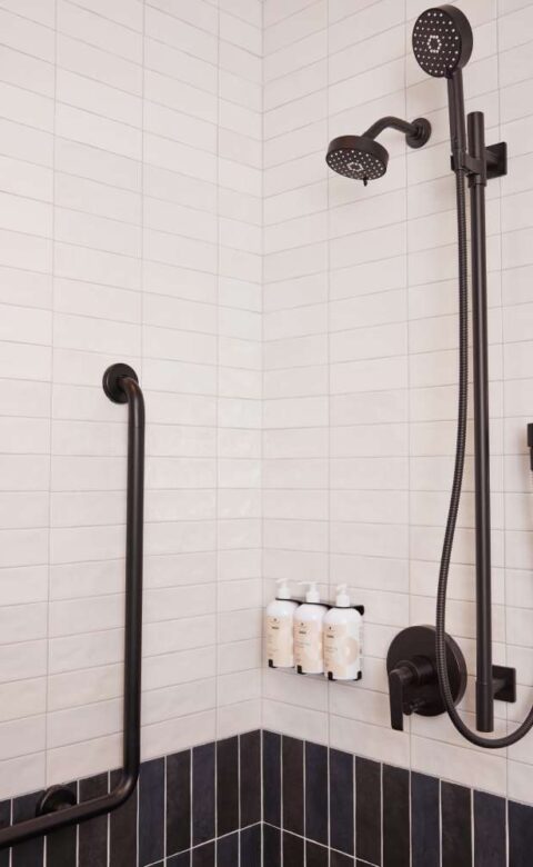 a black and white tiled bathroom with a shower head and hand shower