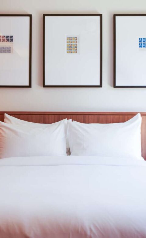 a bed with white sheets and pillows in a bedroom