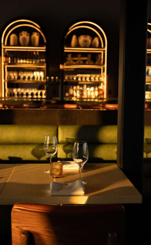 two wine glasses sitting on top of a wooden table in a bar