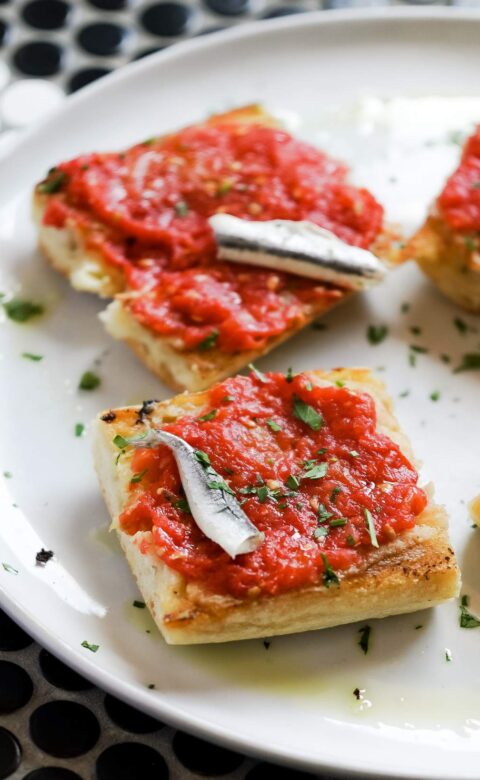 a white plate topped with four pieces of bread covered in marinara sauce