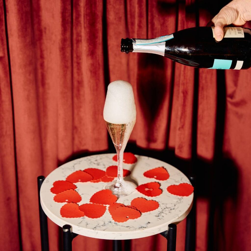 a person pouring champagne into a glass on a table