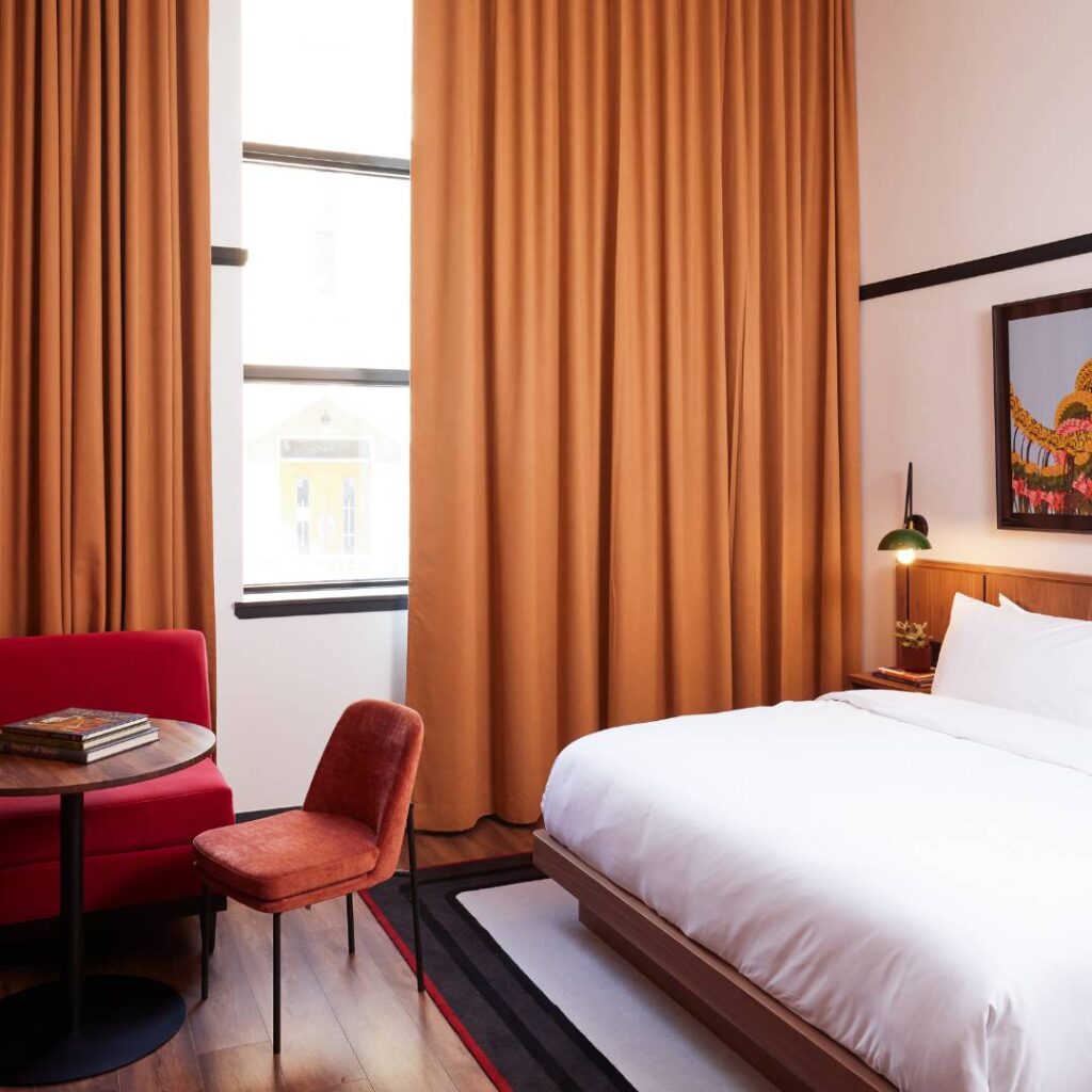 a bedroom with a bed, chair, and window